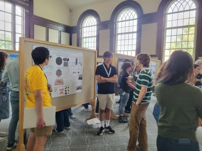 students standing by talking about their research in front of poster